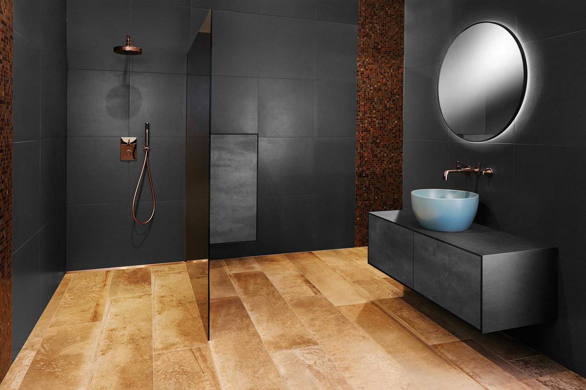 Exklusivität und Extravaganz bringen bronzefarbene Armaturen und die passenden Mosaikelemente in Kombination zum Anthrazit der Wände und einem effektvollen Lichtspiegel. Sabag.