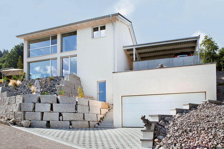Das Haus am Hang ist von zwei Seiten zugänglich und hat sowohl eine Garage als auch einen Carport.