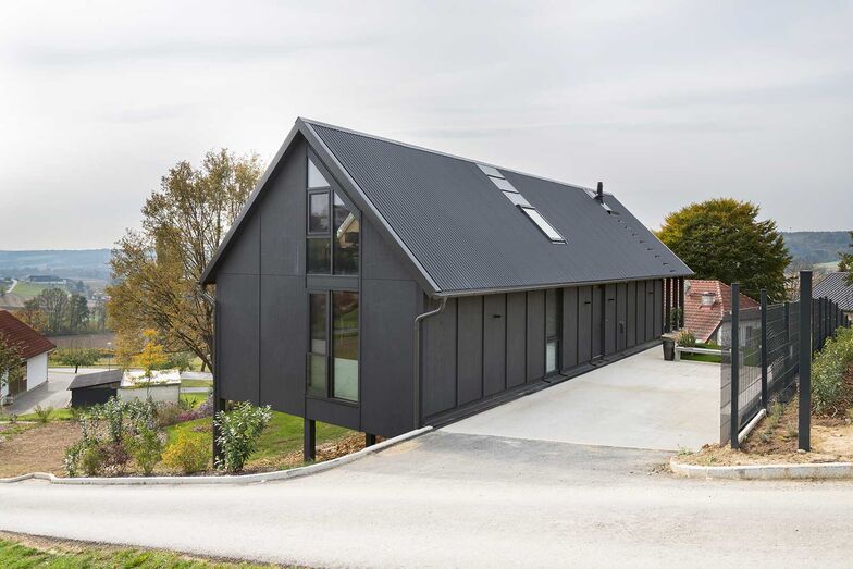 Das Holzhaus «Black Beauty» steht auf dem oberen Rand einer steilen Parzelle, umgeben von Ackerfeldern, alten Bauernhäusern und weiteren Einfamilienhäusern.