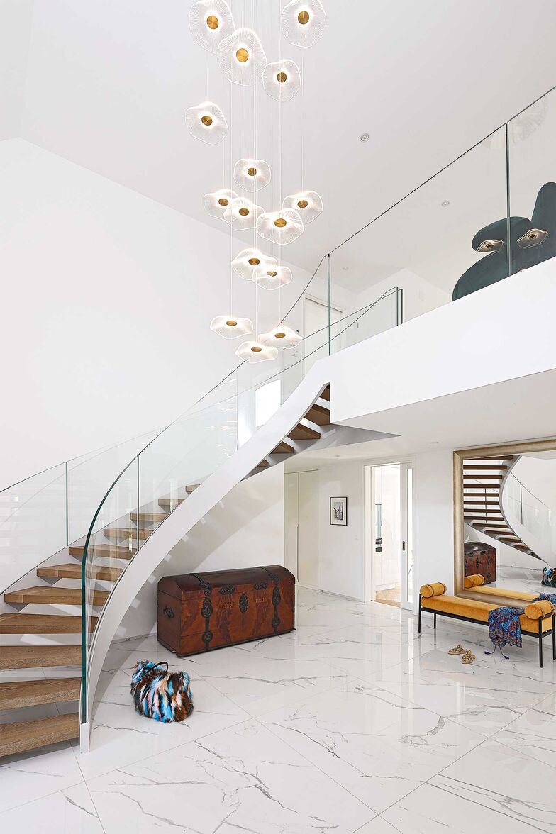 Den Zugang zur Galerie prägen die geschwungene Treppe und die raffinierte Lampe, die von der Decke herabzuwachsen scheint.