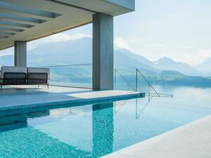 Beim Betonpool mit Panzerglas geniesst man wortwörtlich eine glasklare Aussicht. Die betonierte Treppe führt ins erfrischende Nass, eine Sitzbank sorgt für zusätzlichen Komfort. Nachts kann der Pool dank der Unterwasserbeleuchtung in Szene gesetzt werden. Zireg Ziswiler GmbH.