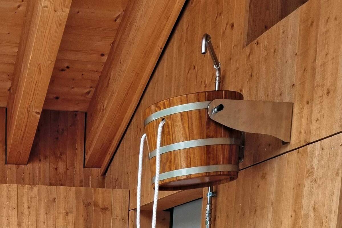 Die «Eimer-Schwalldusche» sorgt nach der Sauna für einen intensiven Kältereiz. Das Wasser, das oben eingefüllt wird, kann per Zug am weissen Seil entleert werden. Angelehnt am rustikalen Design, bietet Fitpa eine moderne Variante des Klassikers. Fitpa AG.