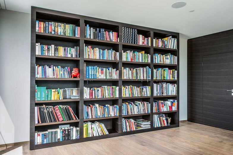 Ganzheitlich gedacht: Beim Innenausbau dieses Hauses wurde ganzheitlich gedacht und geplant. Die Wahl fiel auf dunkle Räuchereiche, welche dem intelligenten, einheitlichen Design Konsistenz und der Wohnung selbst viel Wärme verleiht. Das Material zieht sich durchs ganze Haus und ist unter anderem bei der Wohnwand im Wohnzimmer, beim Bücherregal und in der ans Schlafzimmer grenzenden Ankleide anzutreffen. Stuber Team AG, www.stuberteam.ch